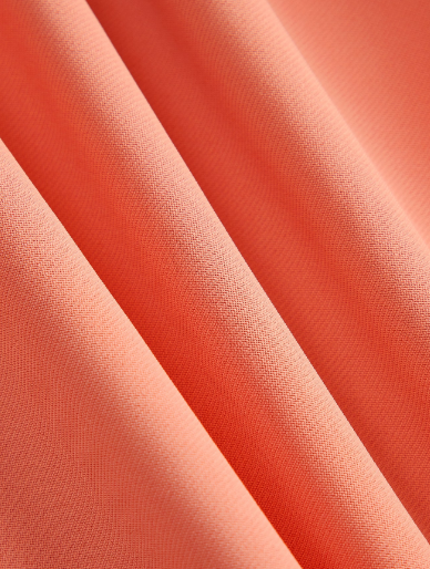 Close do tecido Rosa Coral Suave do vestido midi Plus Size, mostrando textura e acabamento da peça.