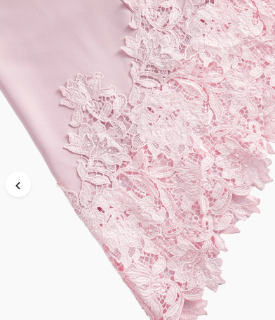 Detalhe da barra assimétrica do vestido Rosa Chá com aplicação de renda floral vazada e acabamento recortado.