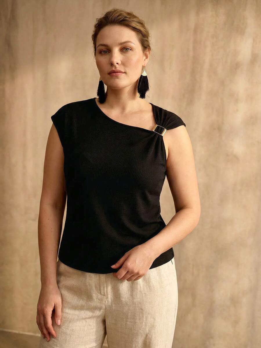 Detalhe do decote assimétrico da blusa feminina com pequena fivela metálica decorativa no ombro plus size