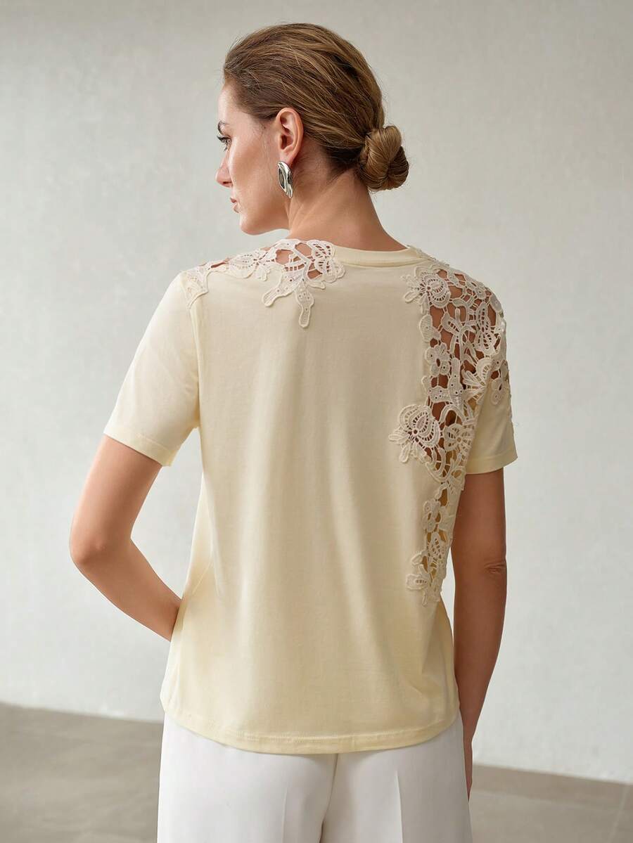 Detalhe da renda floral vazada com desenhos de flores e folhagens aplicada sobre o ombro da blusa