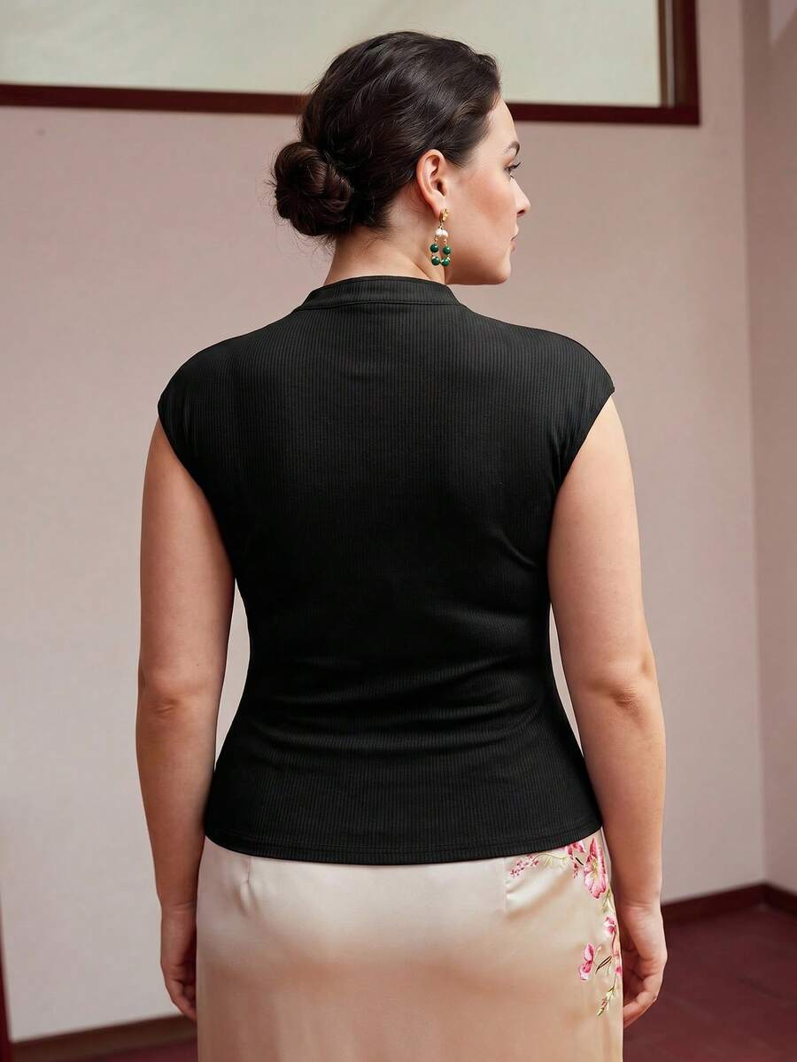 Blusa feminina preta em malha canelada com manga boné, abertura assimétrica no decote e apliques metálicos dourados Plus Size
