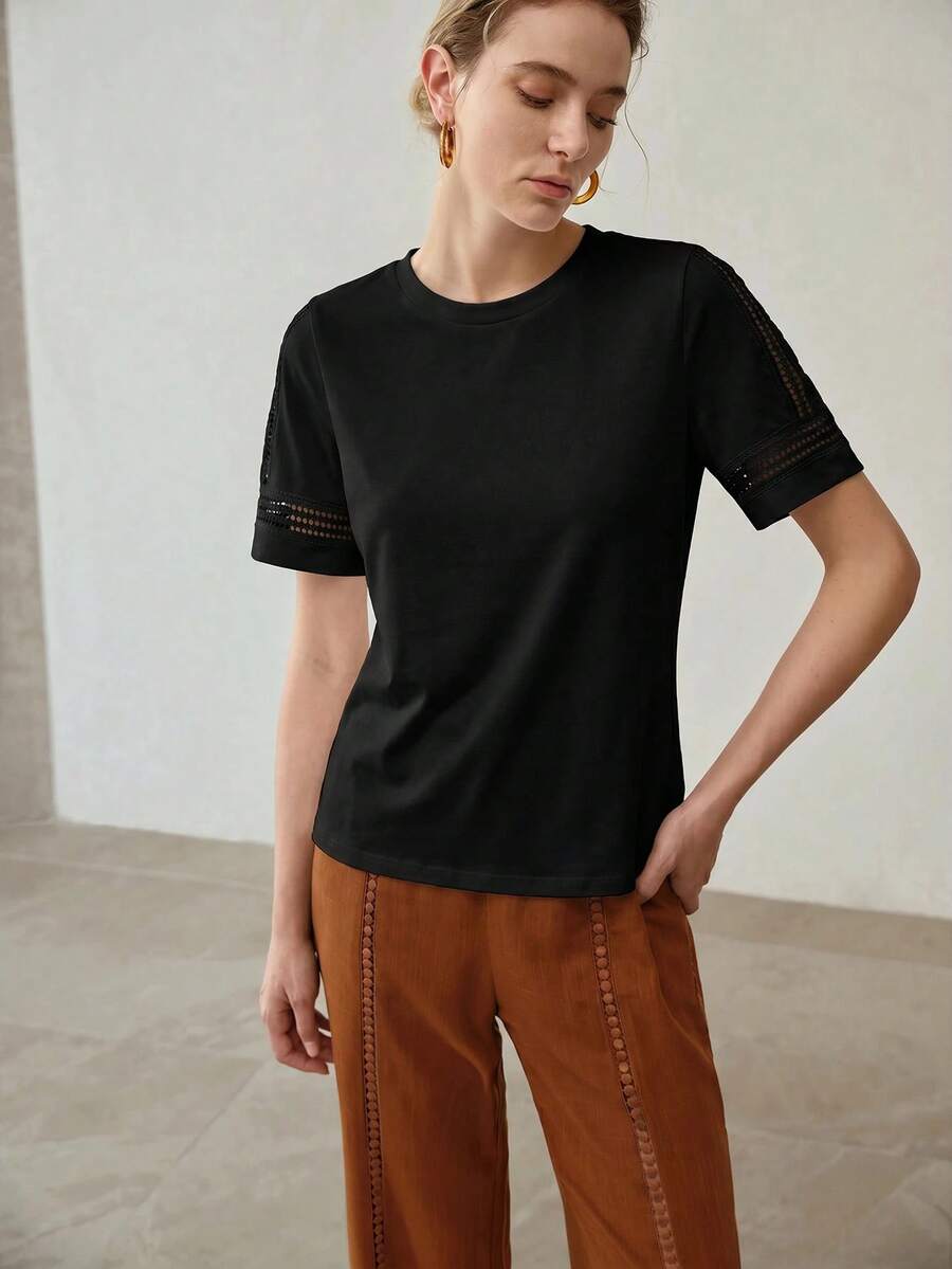 Blusa feminina preta em malha de algodão com gola redonda, manga curta e detalhes vazados decorativos 