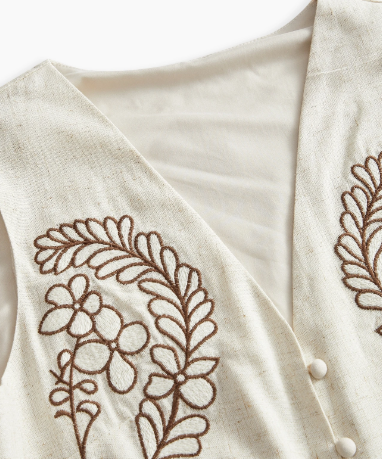 Detalhe do bordado floral marrom na blusa bege