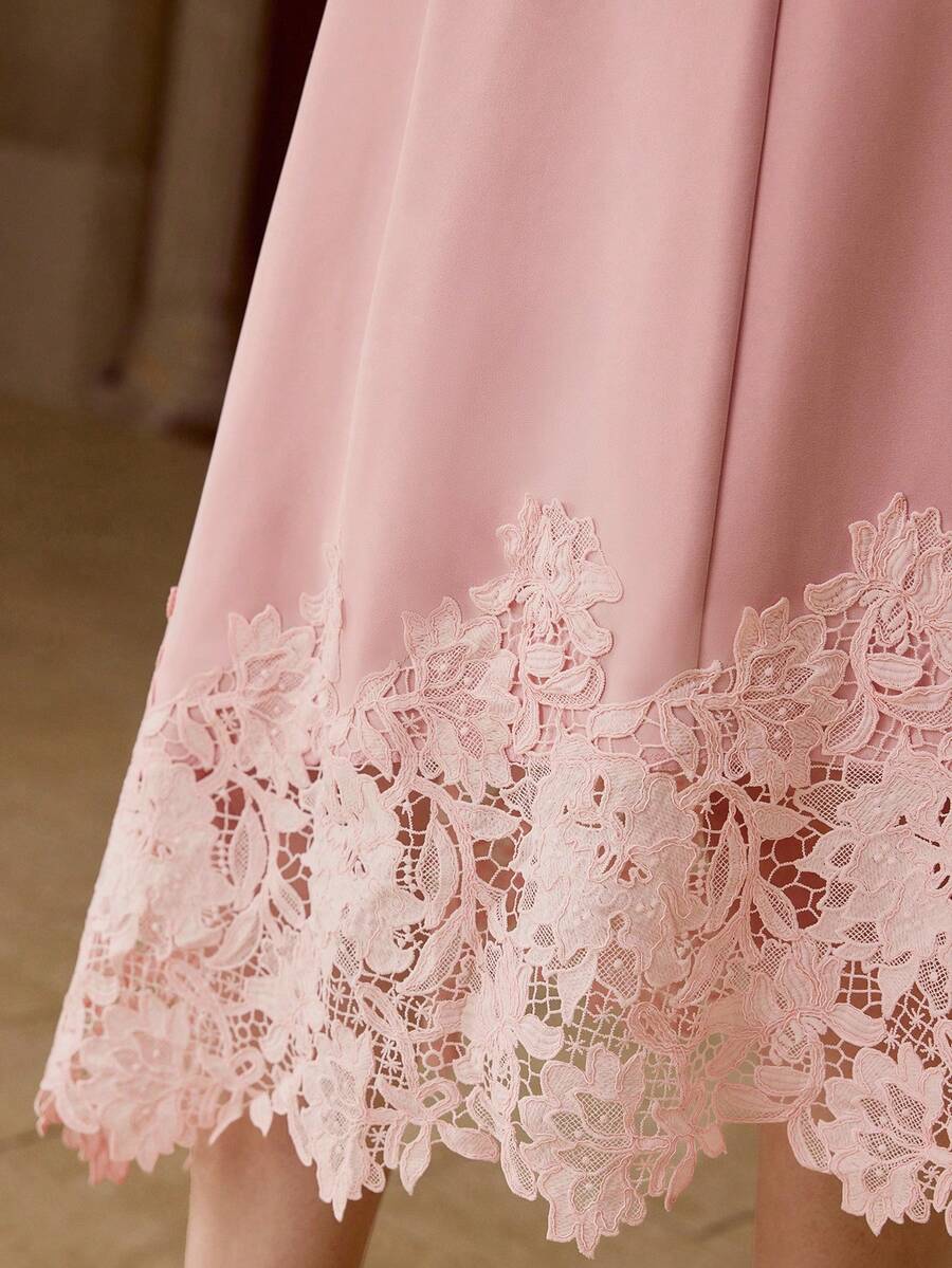 Vestido Rosa Chá com renda floral vazada e comprimento midi assimétrico.