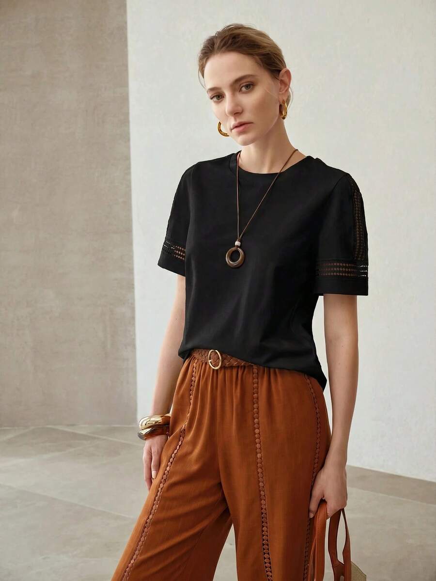Vista frontal da blusa feminina preta em algodão com modelagem regular e detalhes vazados nas mangas